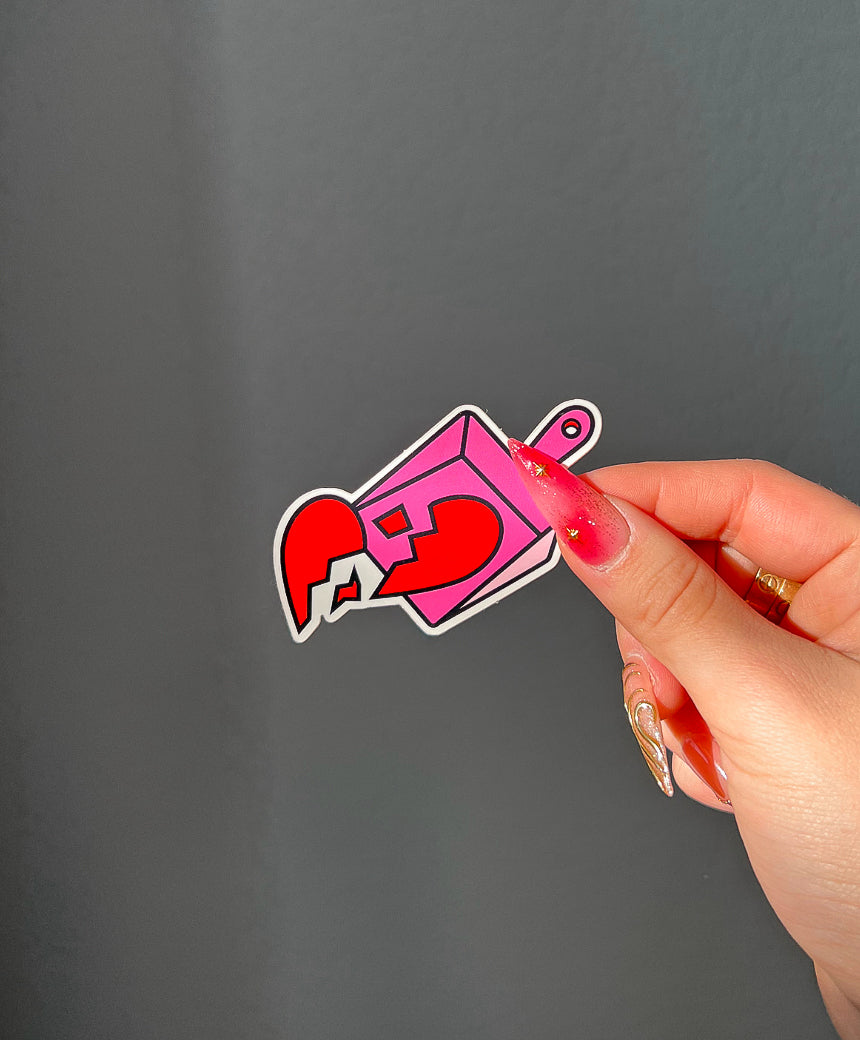 Broken Hearts Sticker next to a hand for size comparison