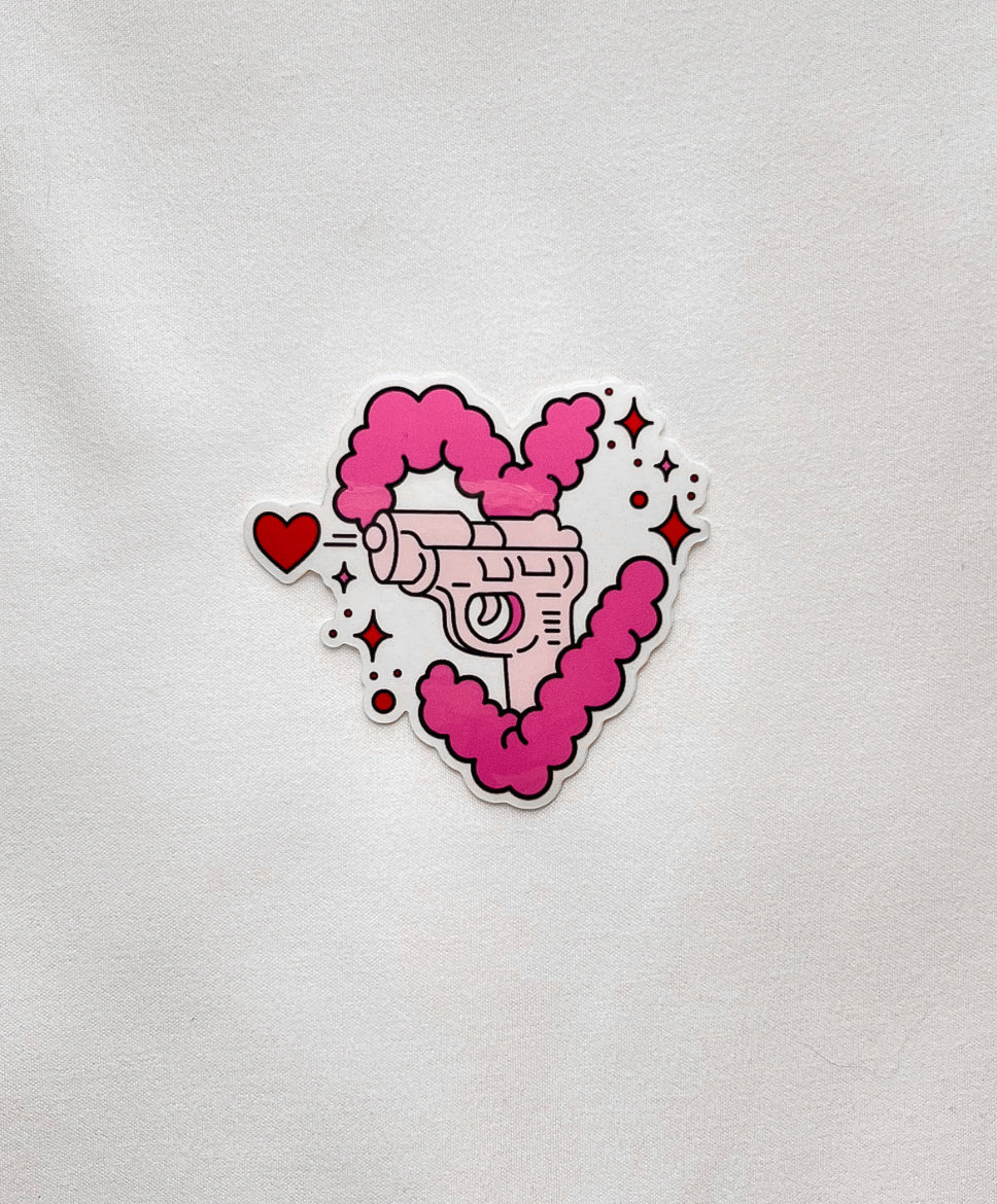 Love Gun Sticker featuring a pink gun shooting a heart, encapsulated in a pink cloud