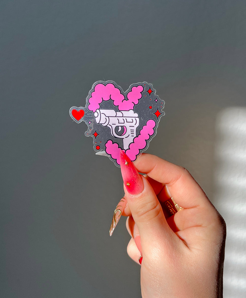 Love Gun Sticker with a transparent background next to a hand for size comparison