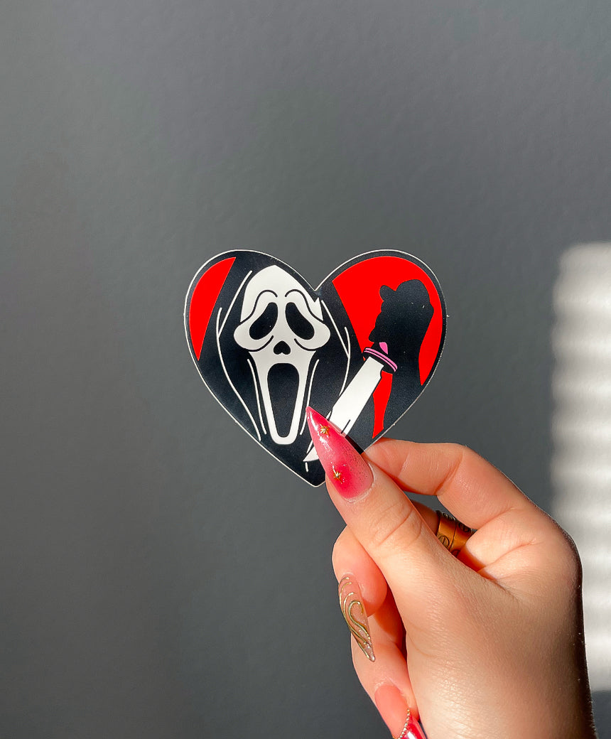 Masked Heart Vinyl Sticker in Red next to a hand for size comparison