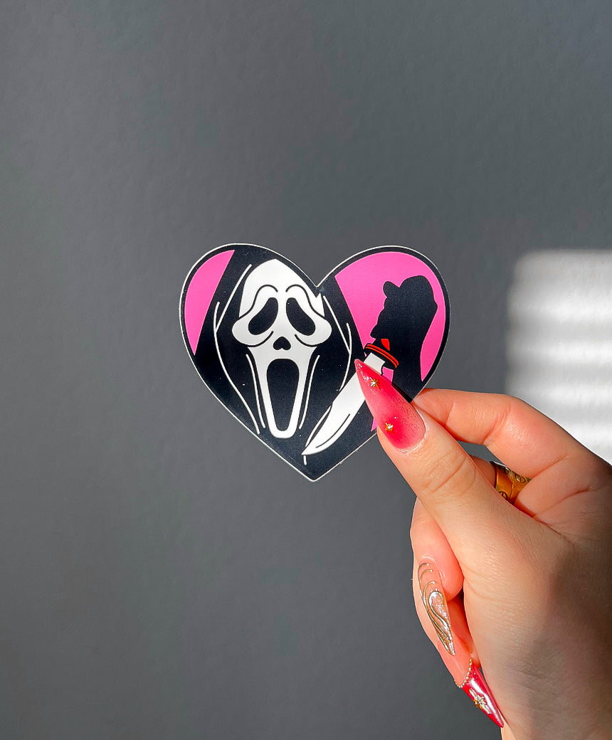 Masked Heart Vinyl Sticker in Red next to a hand for size comparison