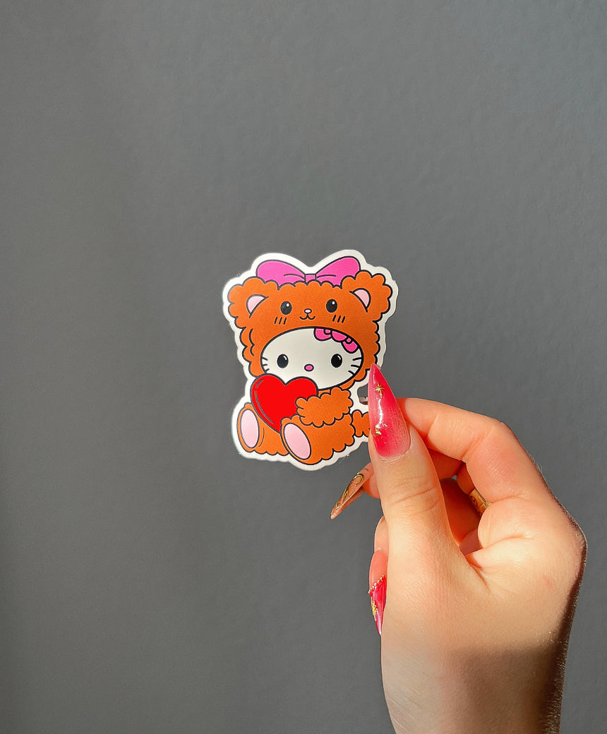 Teddy Bear Kitty Sticker in sunlight next to a hand for size comparison